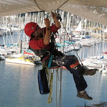 Cordiste en cours de pose d'un filet de sécurité sous le pont.