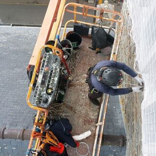 Travaux en hauteur pour sécurisation de façades en béton par pose de filets.